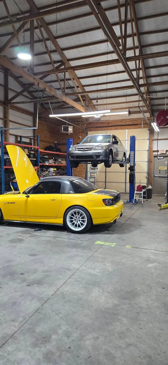 Yellow sports car and project cars inside the Juice Garage shop