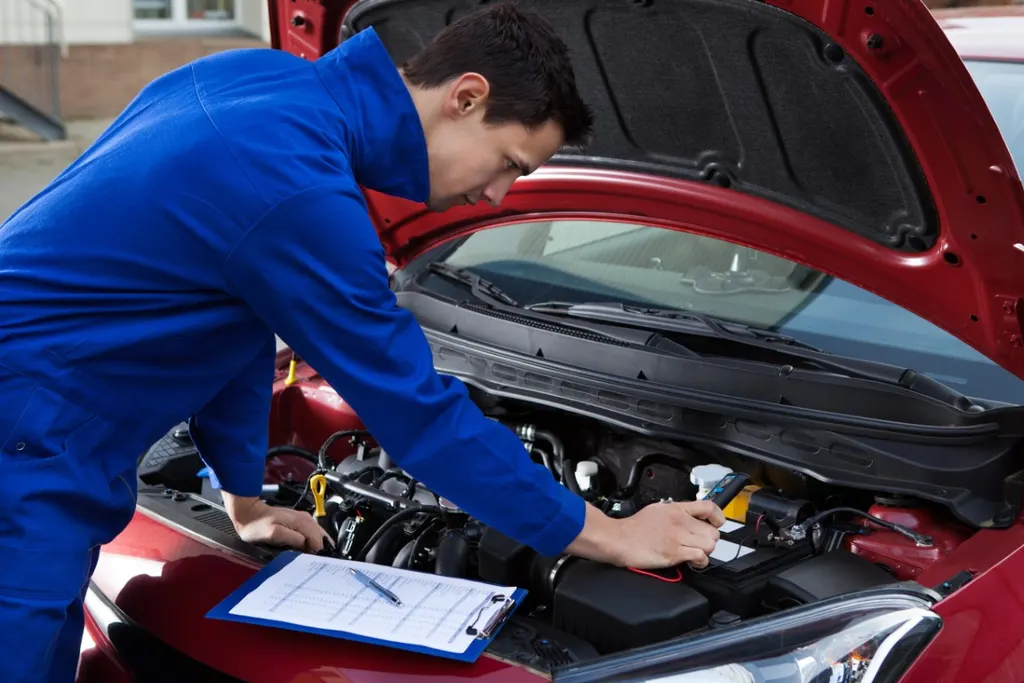 Mechanic working under the hood of a red car